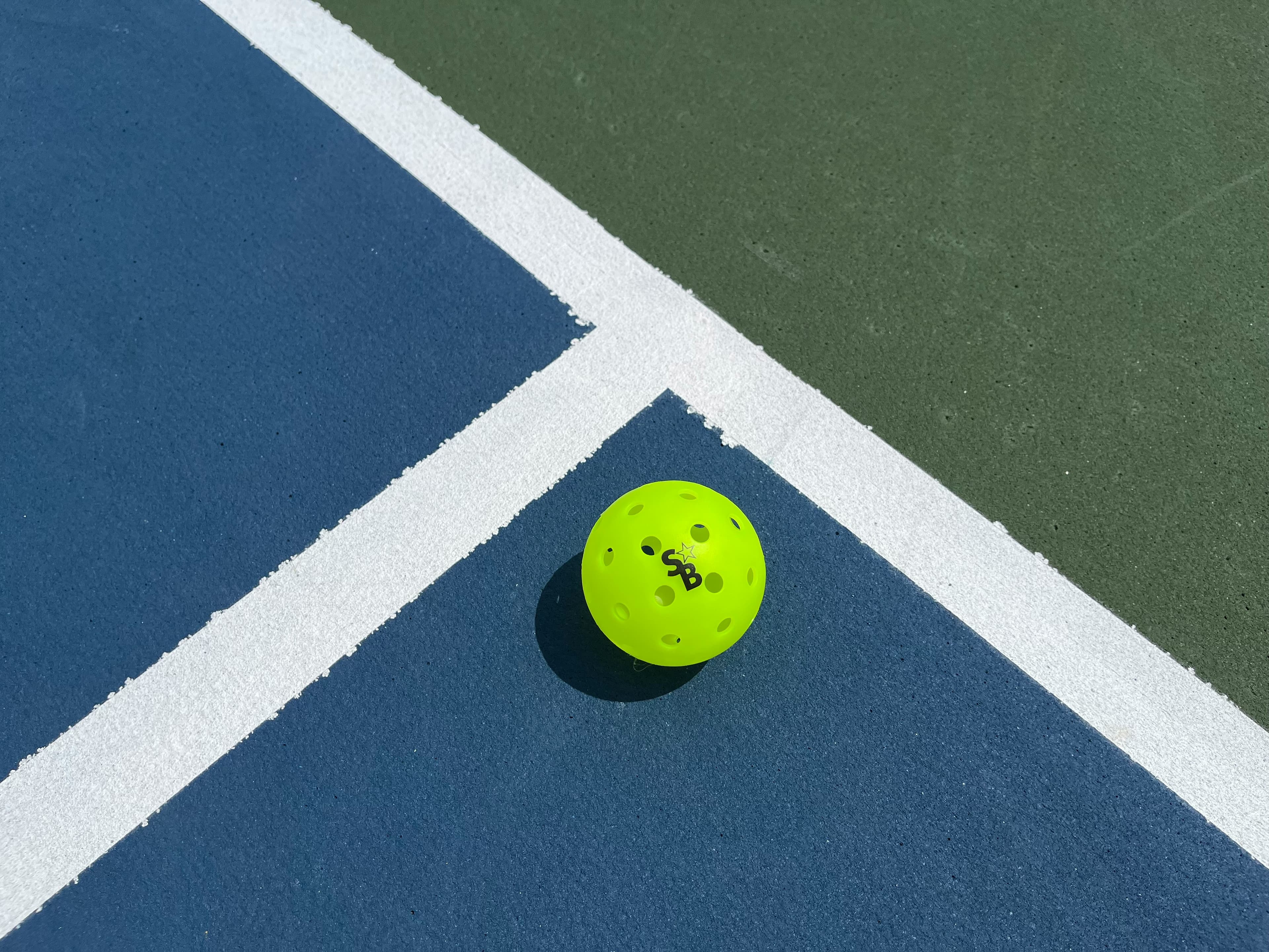 A pickleball resting on a painted court line