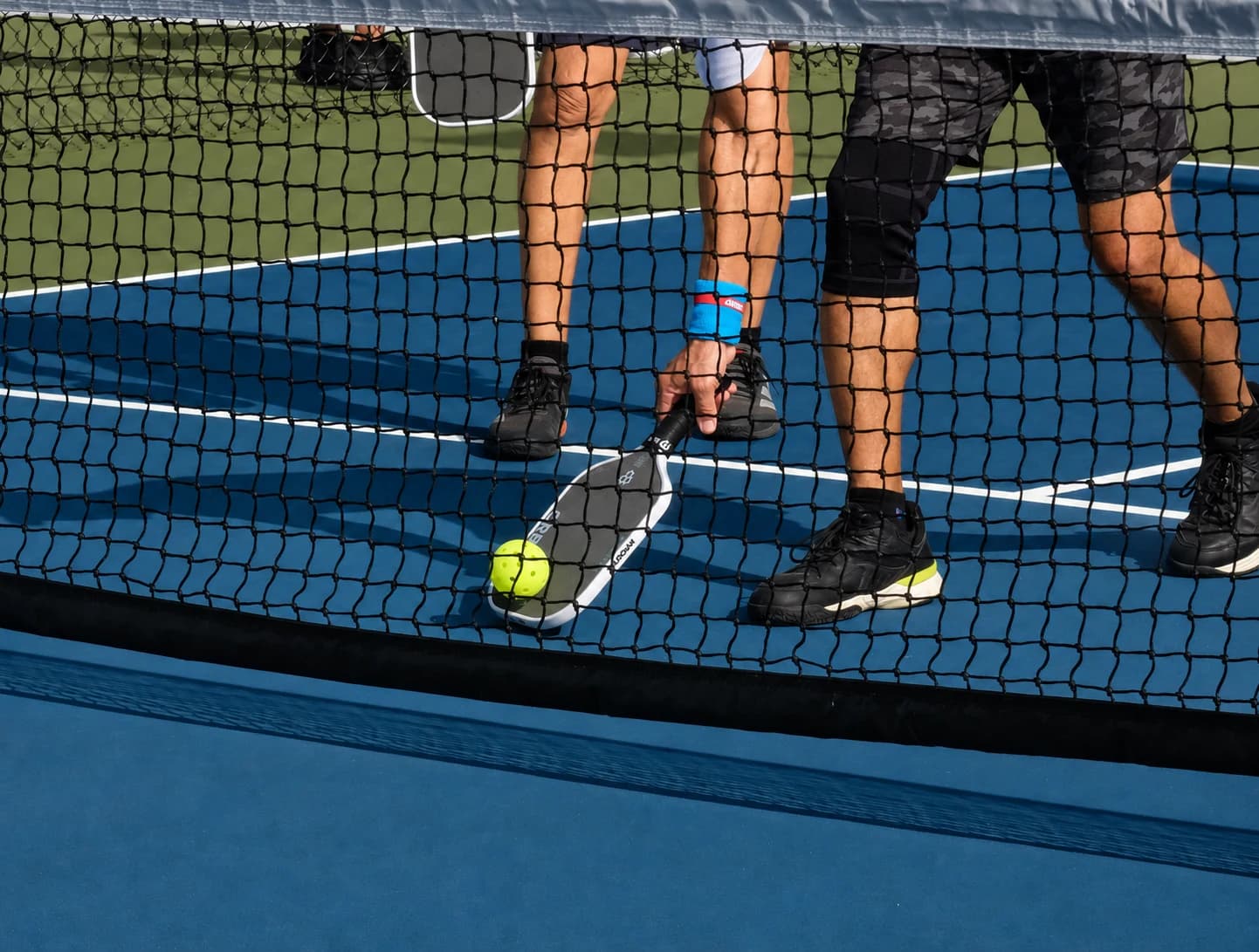 Pickleball players collecting a ball at the net